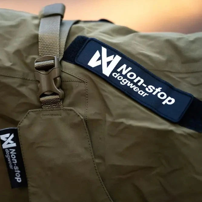 Khaki dog coat with 'Non-stop dogwear' logo on a blurred background