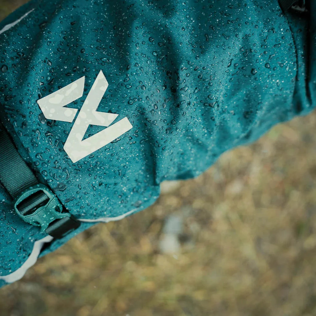 Teal backpack with a logo on a rocky surface